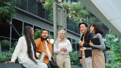 Business team talking and taking a break outside at a green office space