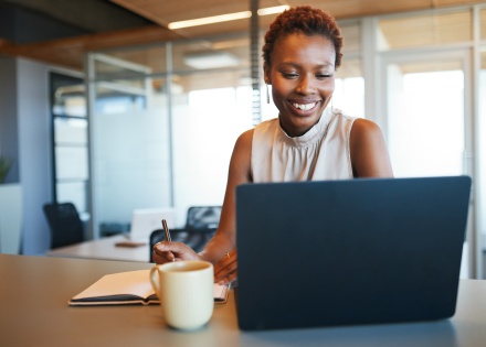 Businesswoman working on a laptop and taking notes in an office