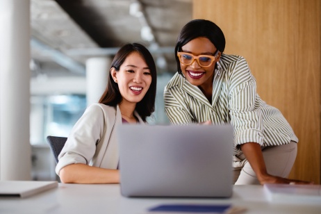 Two professional women discussing global HR compliance on a computer