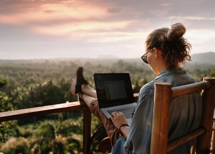 Digital nomad working on her laptop on a balcony