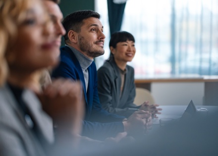 Four engaged employees sitting at a work table listening to a presentation on equity management.