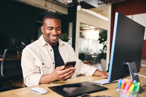 Male bookkeeper working in an office and looking at his phone
