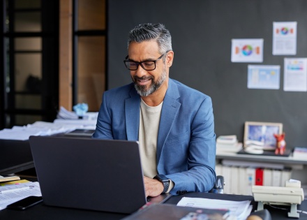 Adult businessman smiling while working on his laptop