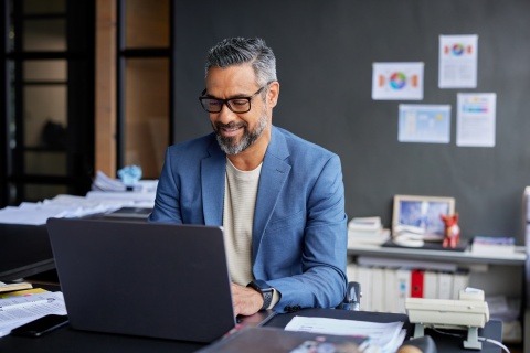 Adult businessman smiling while working on his laptop