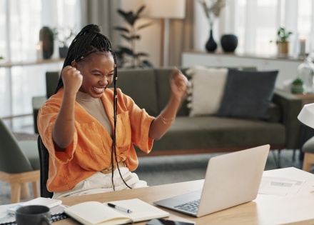 Woman cheering at her laptop while learning about types of cryptocurrencies